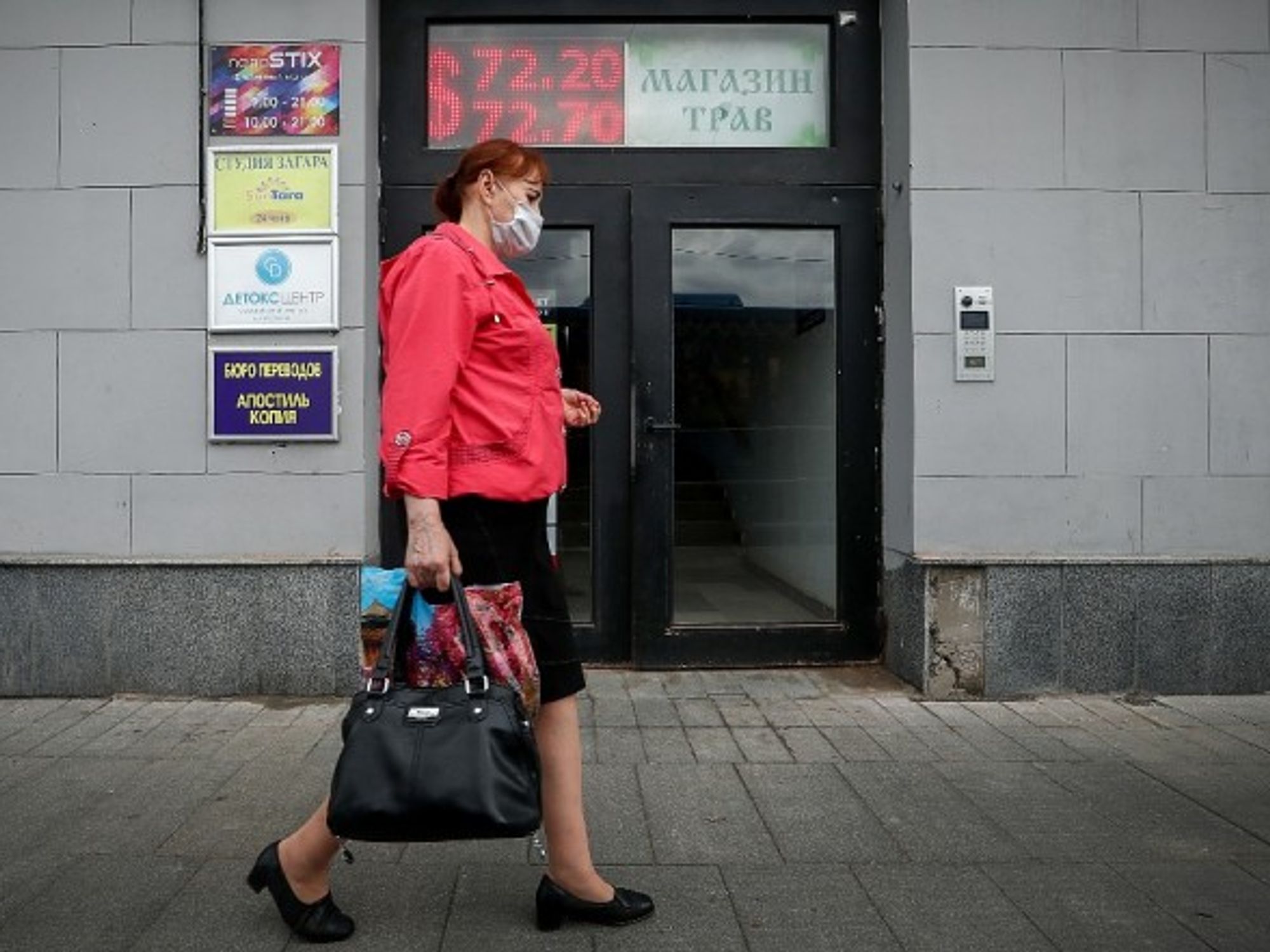 A woman passes a currency exchange office in Moscow, Russia