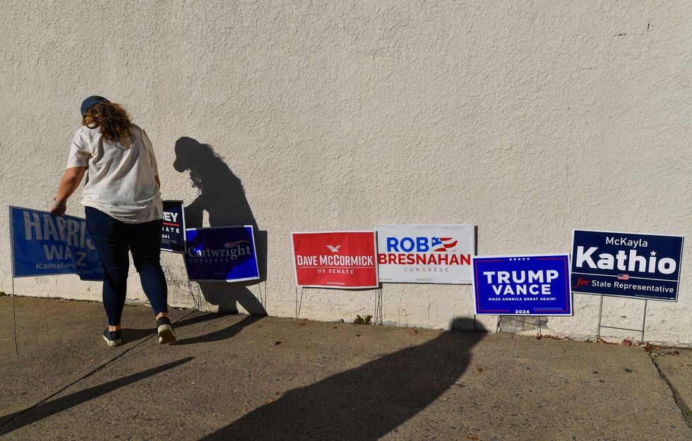 A woman places campaign signs outside of the Moosic polling place.