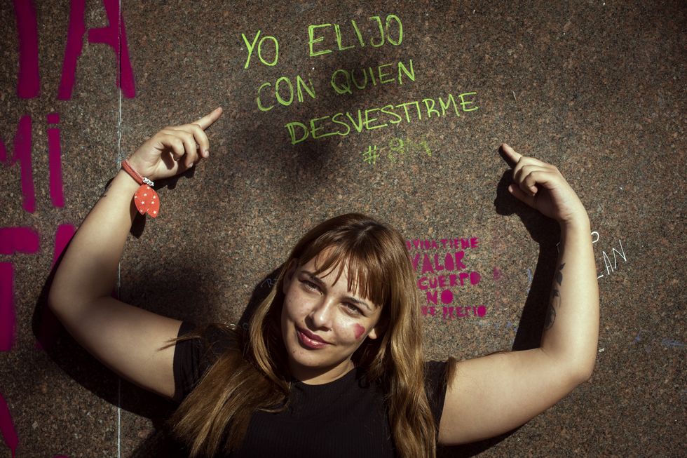 A woman pointing to a sign saying "I choose who to undress with" at the Buenos Aires women's rally against domestic violence.
