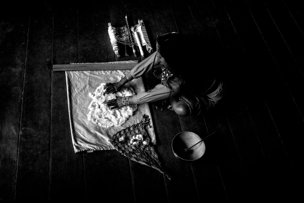 A woman prepares cotton for weaving.