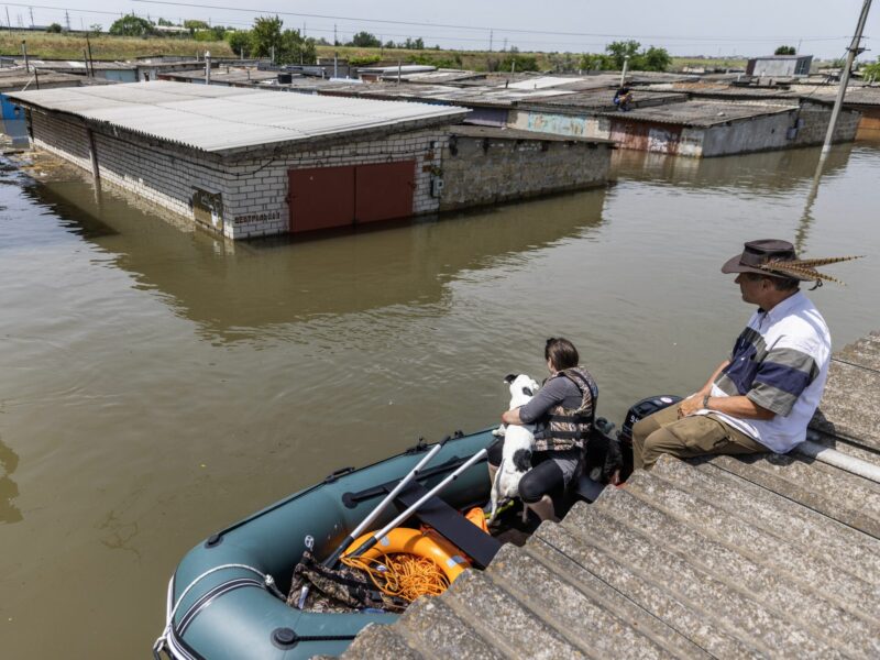 A woman rescues a dog in Kherson, Ukraine, amidst floods.
