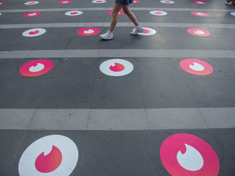 A woman seen walking past Tinder logo markers in Bangkok.​