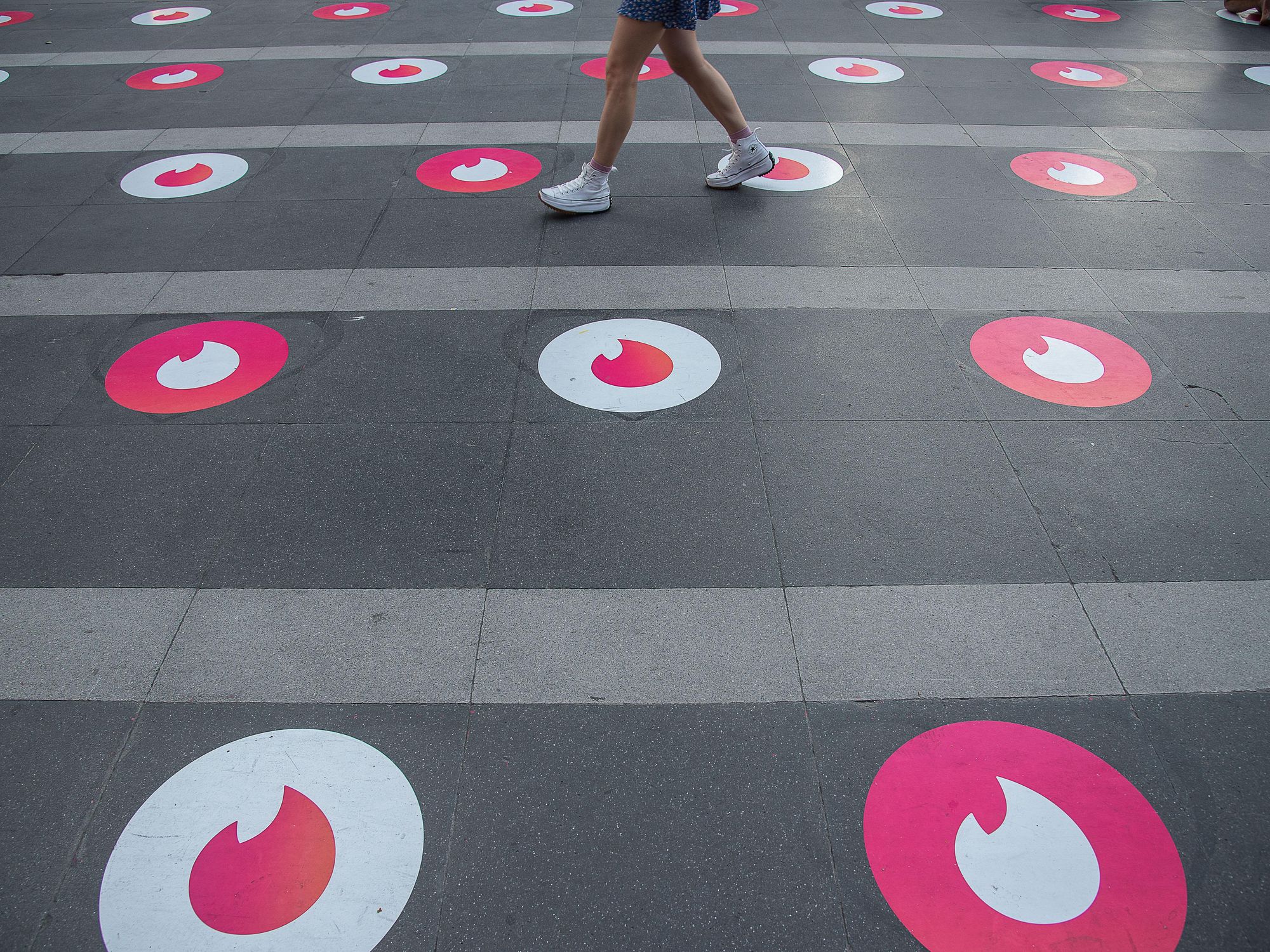 A woman seen walking past Tinder logo markers in Bangkok.​