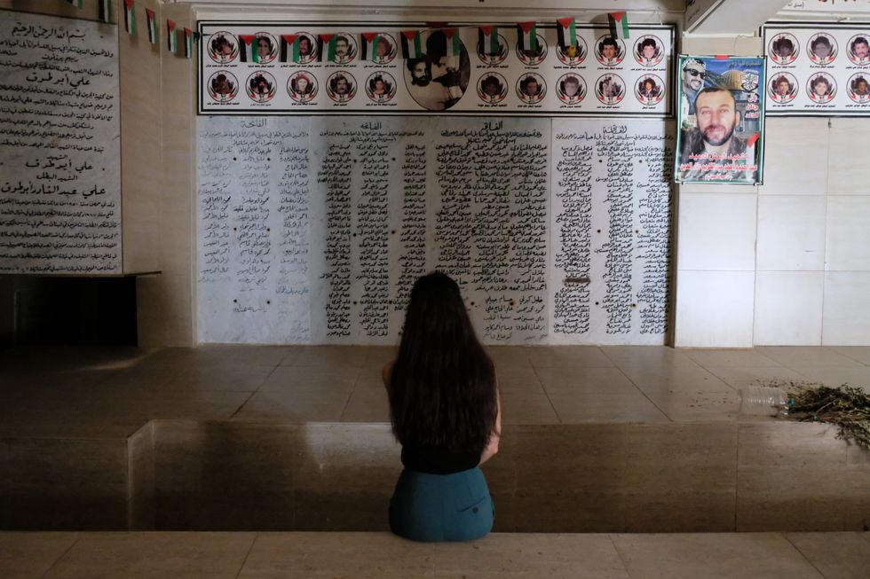 A woman sitting down in front of a morial for Chatila massacre.