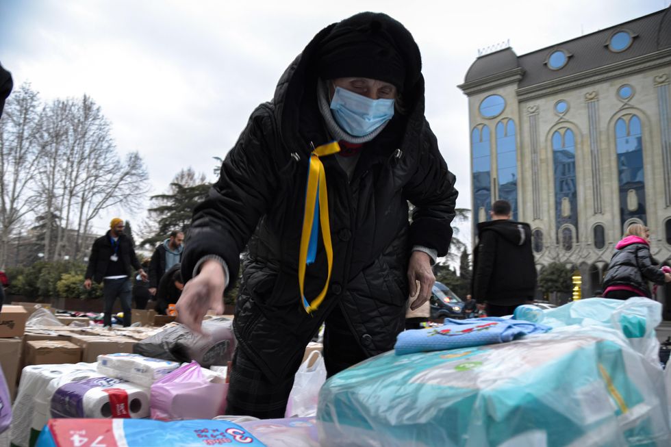 a woman sorts out supplies left by georgian demonstrators for people in Ukraine in front of the Parliament in Tbilisi