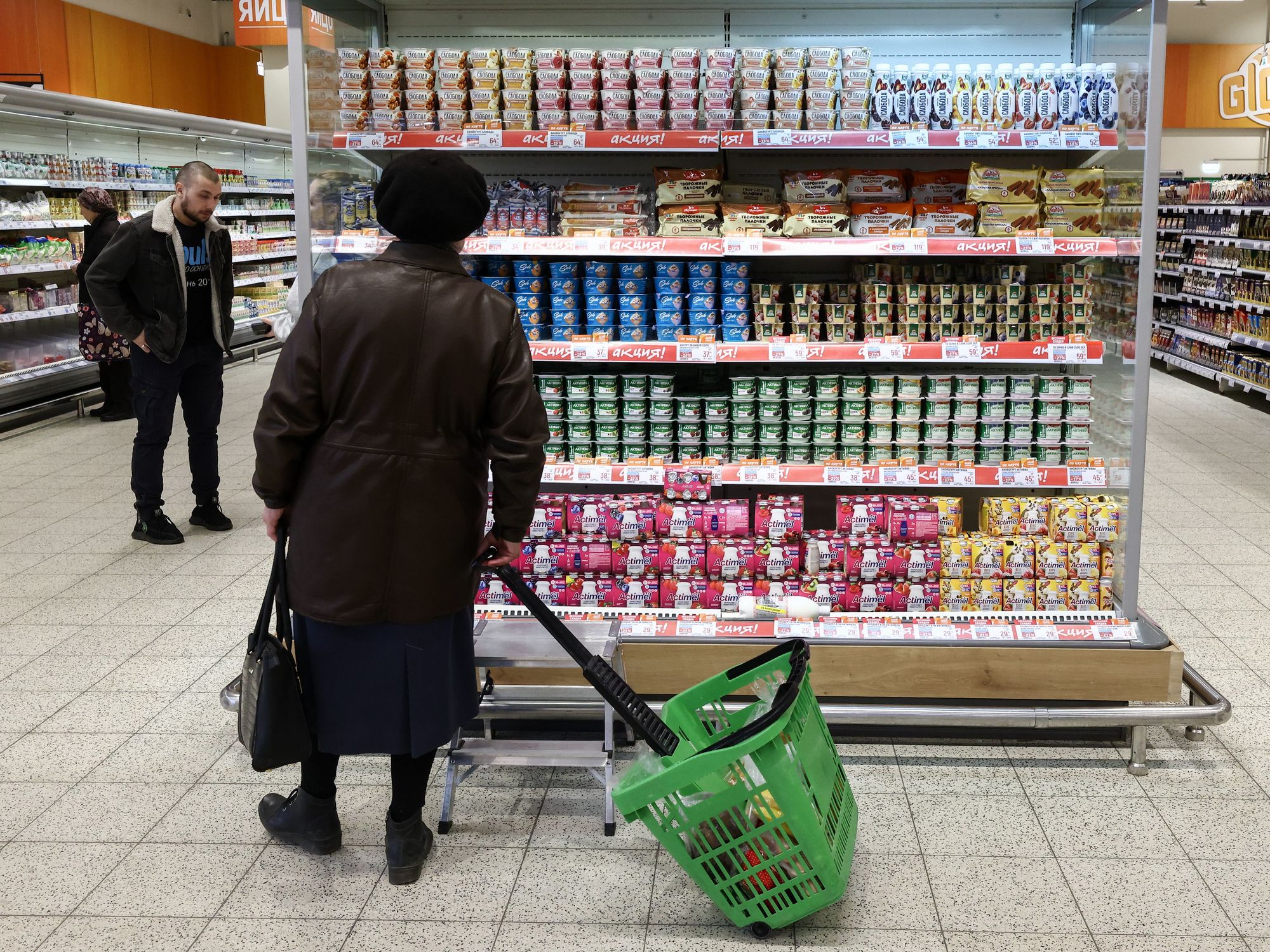 A woman stands in front of Danone and dairy products in a supermarket in Russia.