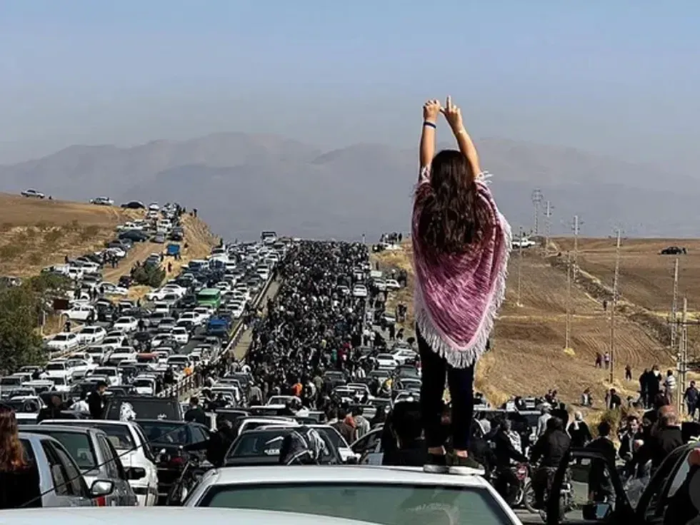 A woman stands on a car during a protest.