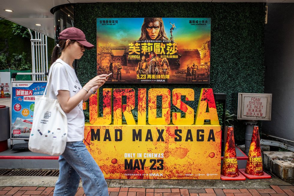 A woman strolls past a petrol station in Quarry Bay as part of a promotional tie-in between SINOPEC and Warner Bros.