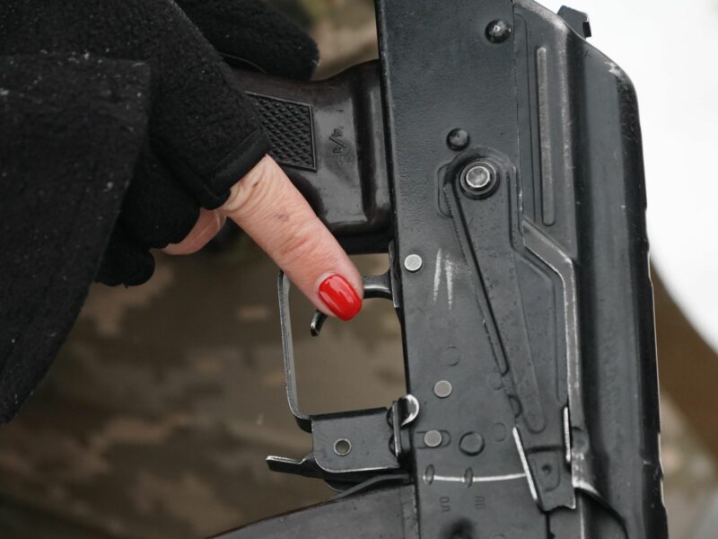 A woman volunteer handles a weapon as civilian volunteers of the Obukhiv Civilian Protection force train together​