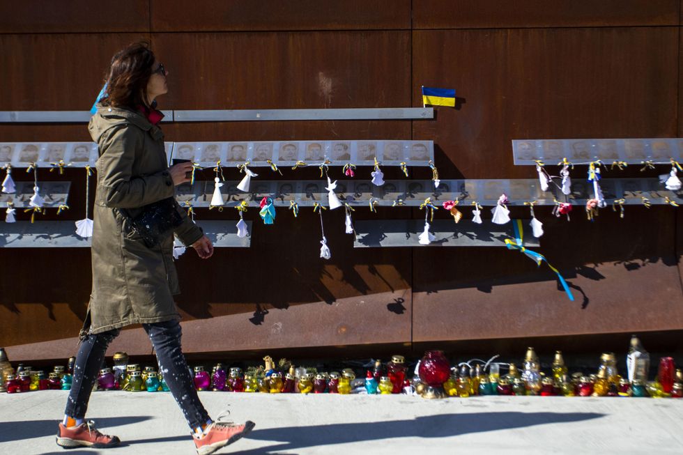 A woman walks by a memorial for Ukrainians killed in the 2014 revolution in Lviv