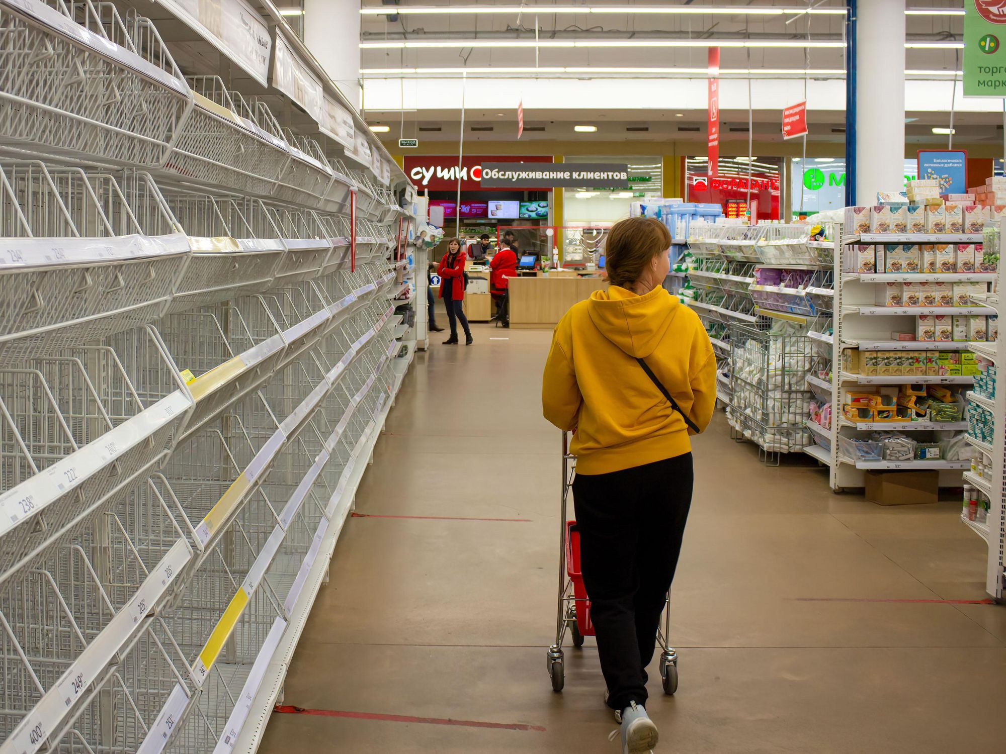 A woman walks by empty shelves in a supermarket in Moscow.​