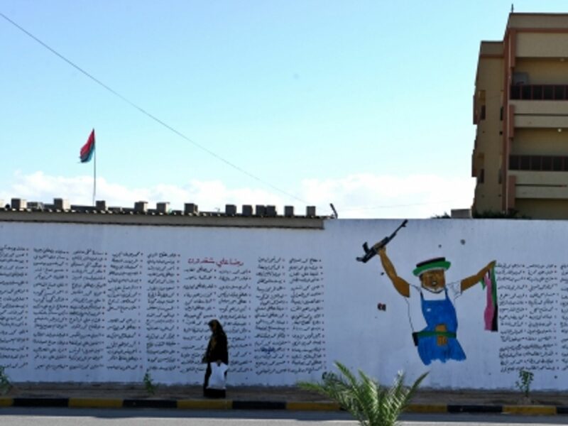 A woman walks past a wall full of names of people who died during the Libyan Civil War, in Misrata.