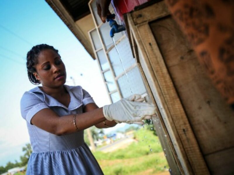A woman washes her hands outside a community health center in Ebola-affected Freetown.