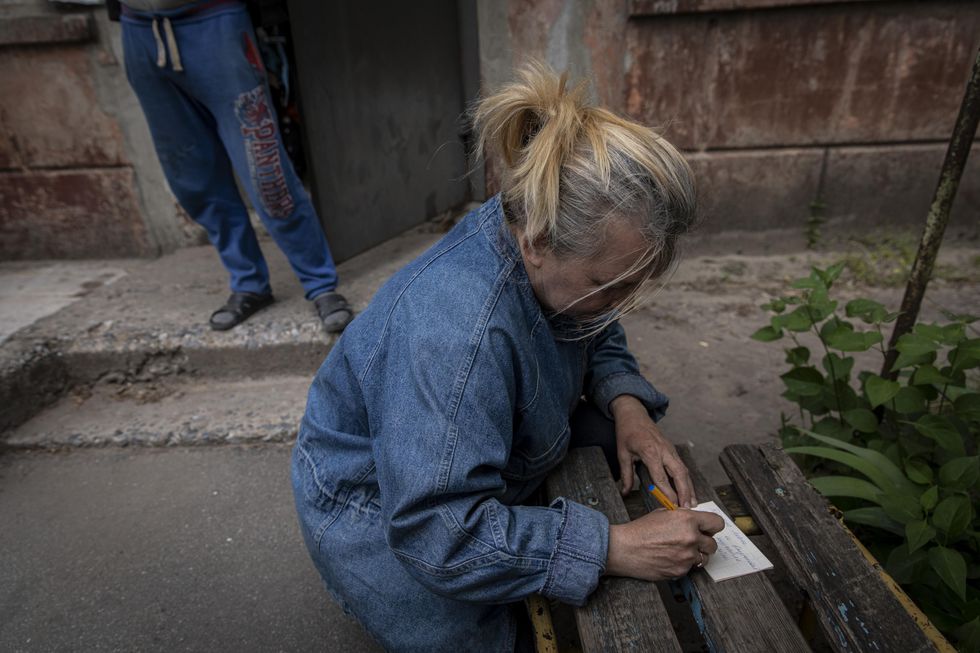 A woman writes down her children's names, as she can't contact them due to lack of internet signal in Severodonetsk, Ukraine.