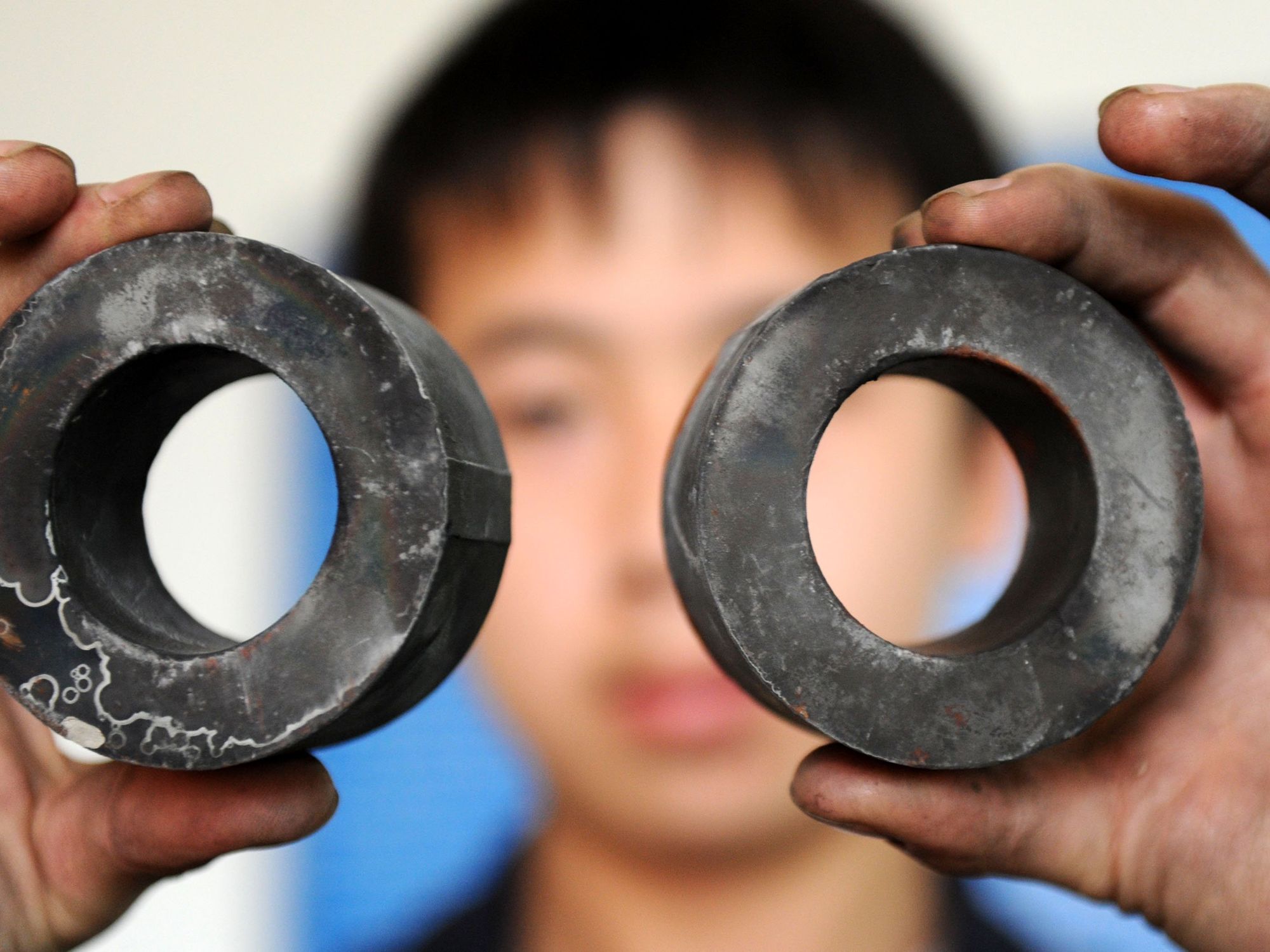 A worker holding up two disks of rare earth metals.