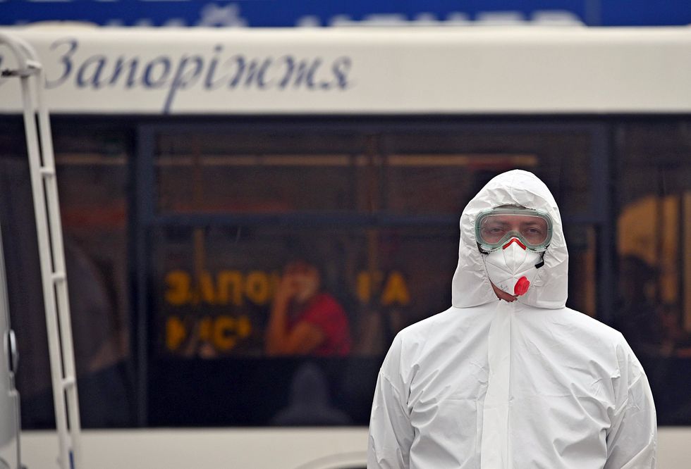 A worker in a protective suit and gas mask