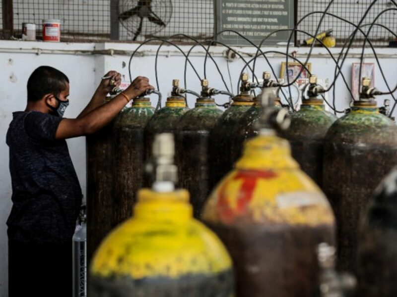 A worker refills medical oxygen cylinders at a charging station in New Delhi, India, where a surge in new cases has prompted an oxygen shortage.