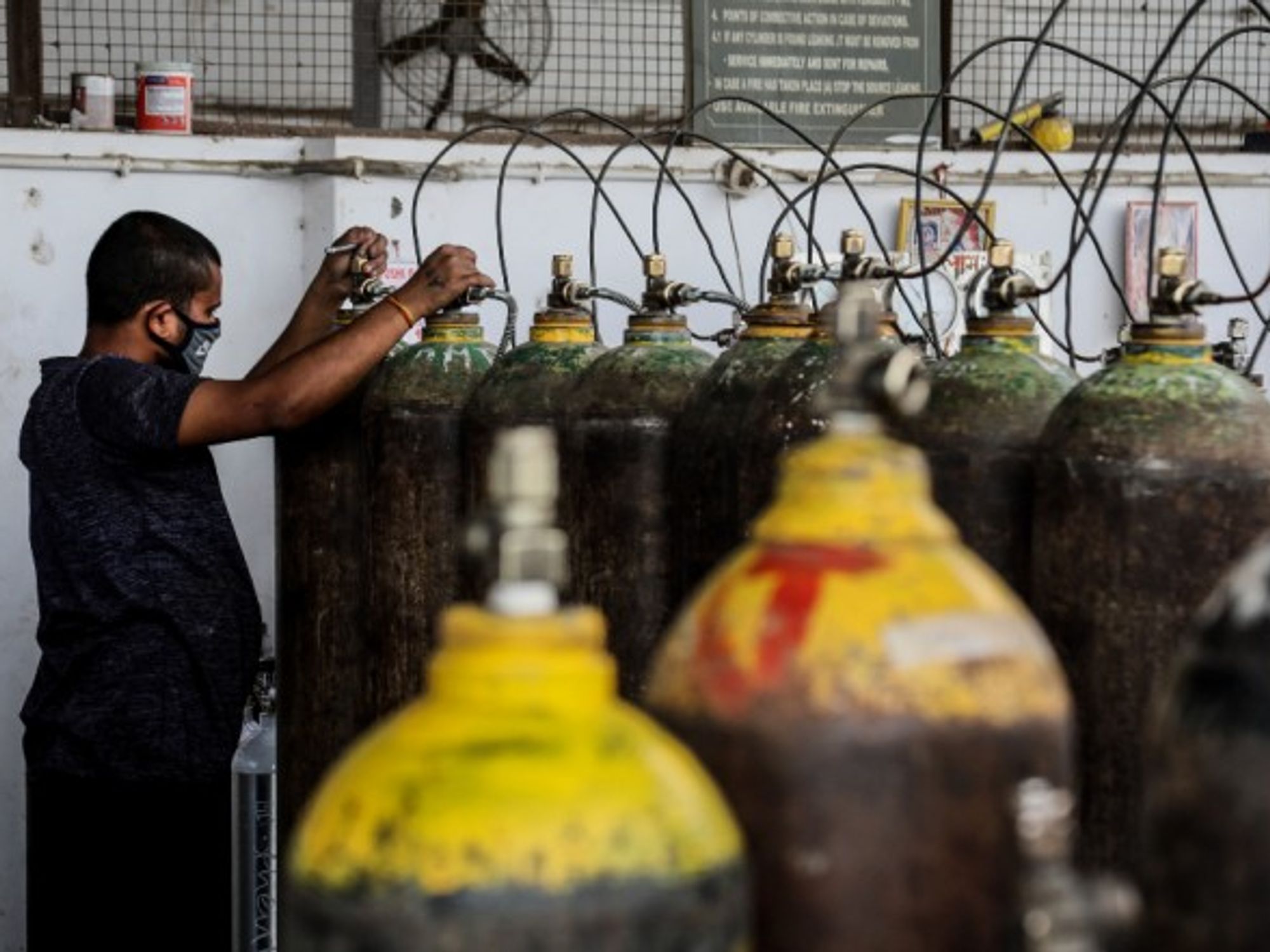 A worker refills medical oxygen cylinders at a charging station in New Delhi, India, where a surge in new cases has prompted an oxygen shortage.
