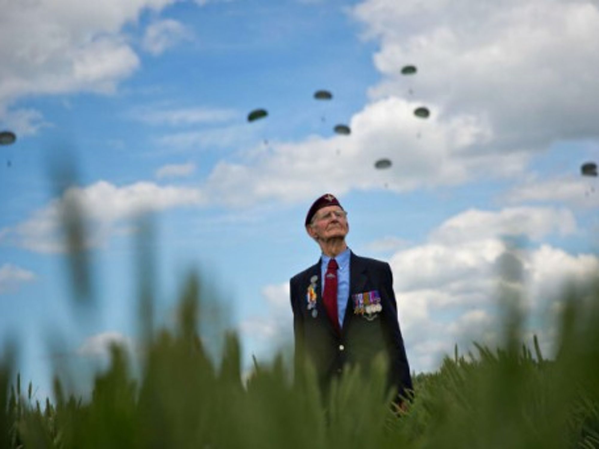 A WWII veteran watches a landing by paratroopers in Ranville, Normandy
