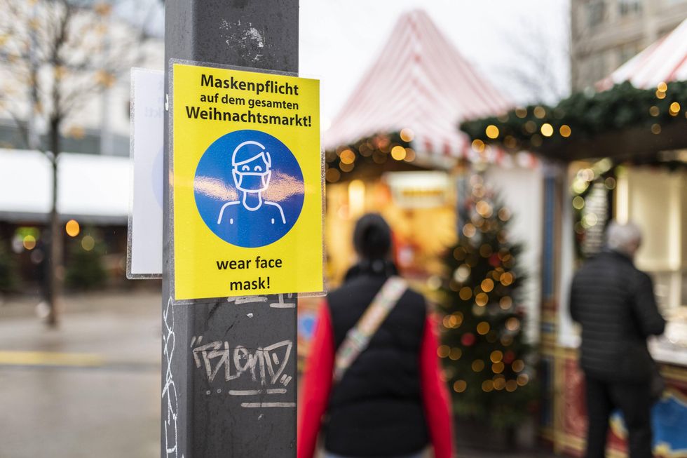 A yellow ​"Wear face mask!" sign in Alexanderplatz in Berlin