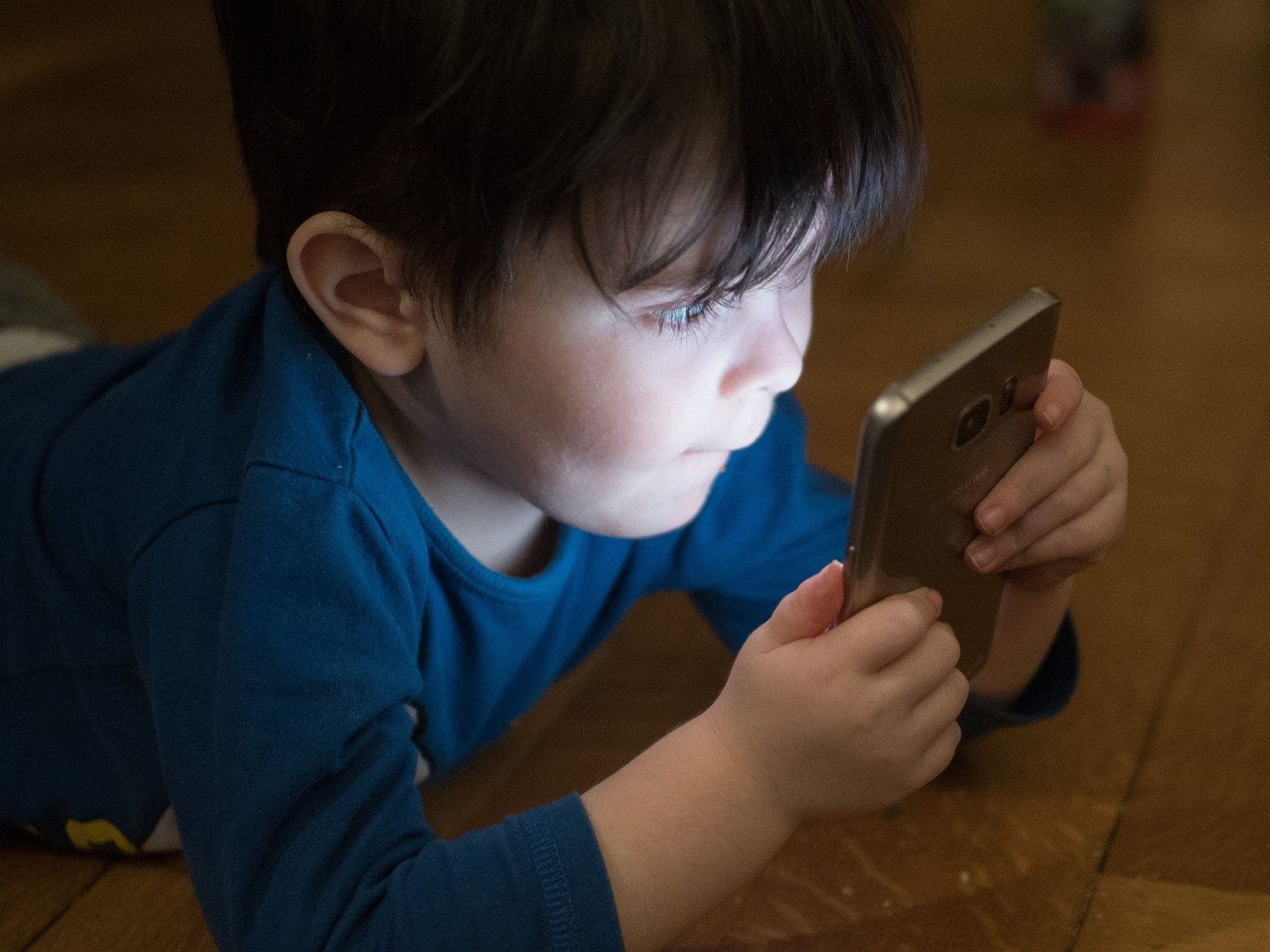 a young boy looking at a smartphone