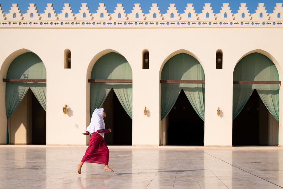 A young Egyptian girl runs inside the courtyard of Al-Hakim Mosque in Cairo, Egypt.
