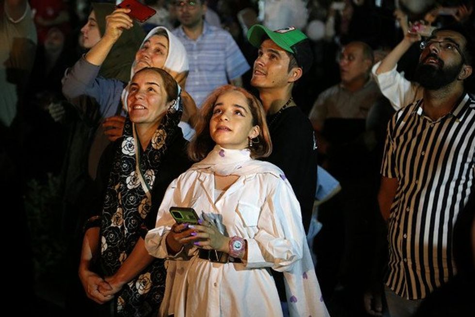 A young Iranian girl without wearing a mandatory headscarf looking at fireworks.