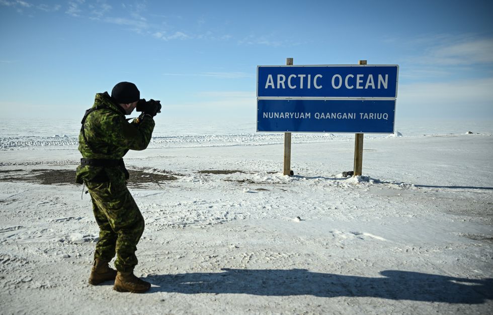 A young man takes a photo of a sign that reads ''Arctic Ocean'' in Tuktoyaktuk in the Arctic.