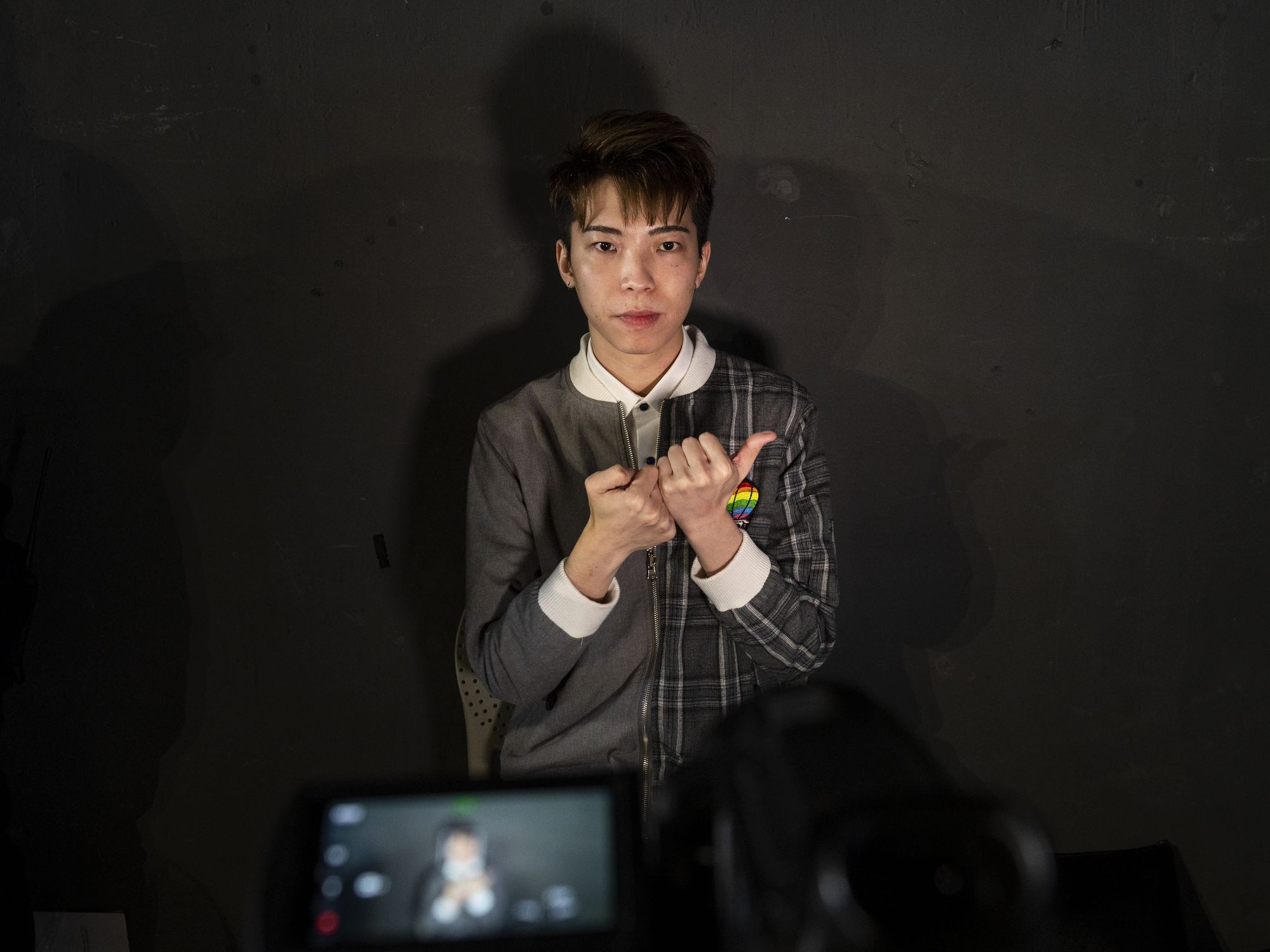 A young person signs to a camera infront of a black background