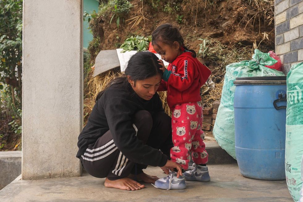 A young woman tying shoelaces for her small daughter
