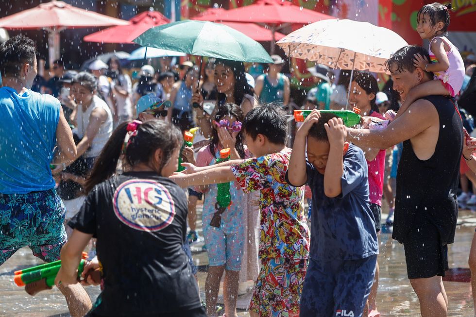Adults and kids in swimsuits play water guns amid extreme hot weather, at Ocean Park in Hong Kong.