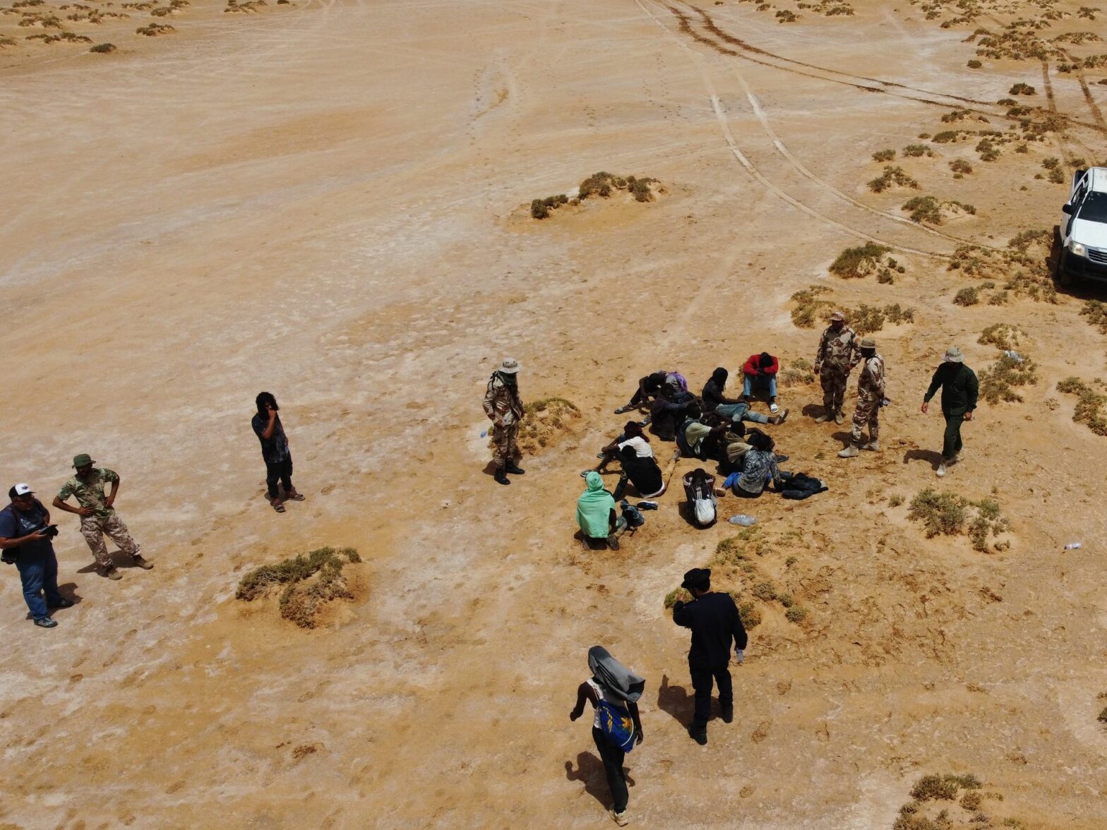 Aereal photograph of Staff members of the desert patrols of the Libyan Illegal Immigration Control Department and some stranded African migrants at the Libya-Tunisia border