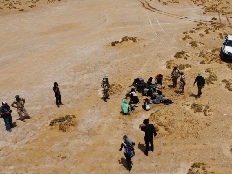 Aereal photograph of Staff members of the desert patrols of the Libyan Illegal Immigration Control Department and some stranded African migrants at the Libya-Tunisia border