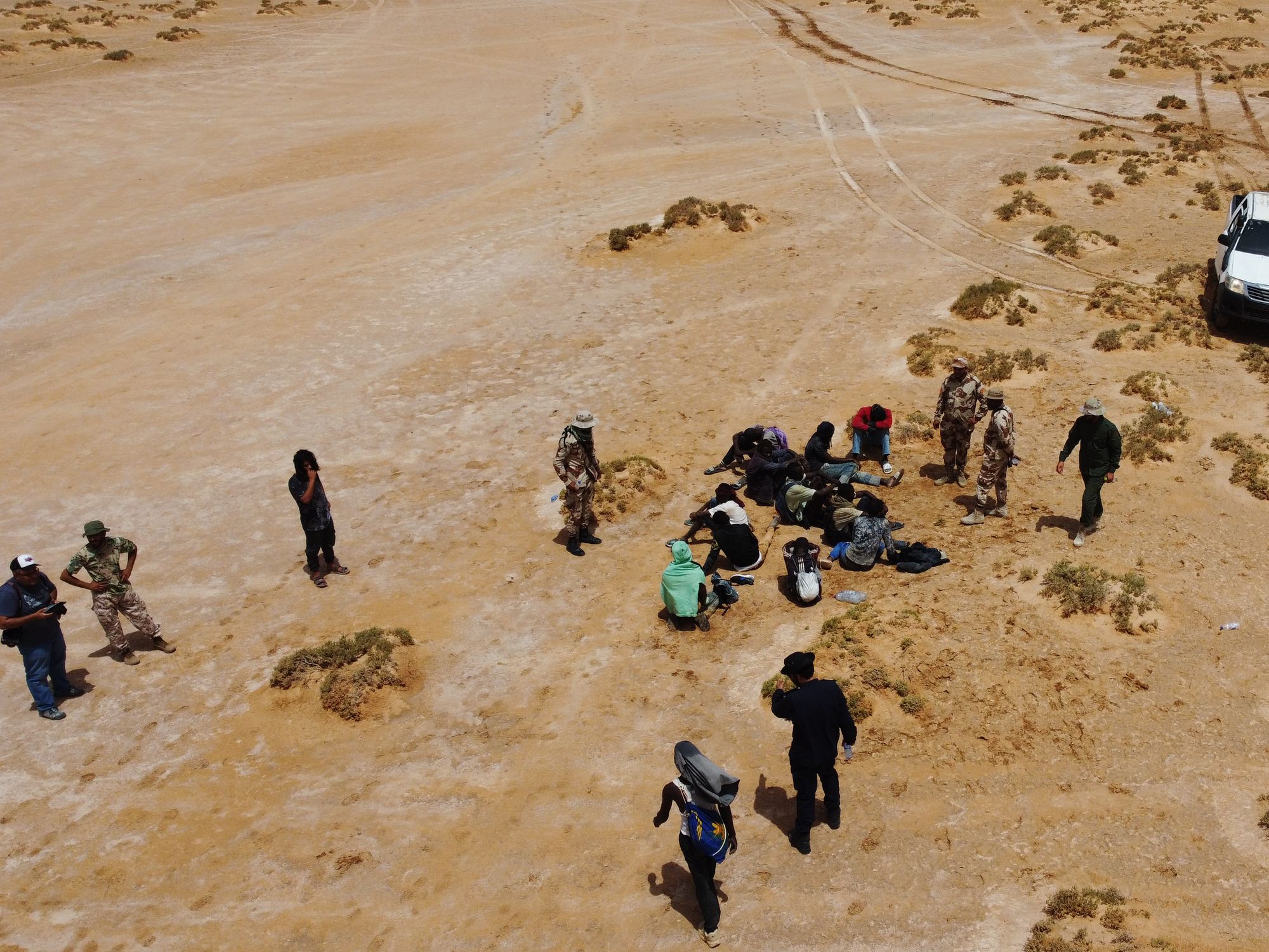 Aereal photograph of Staff members of the desert patrols of the Libyan Illegal Immigration Control Department and some stranded African migrants at the Libya-Tunisia border