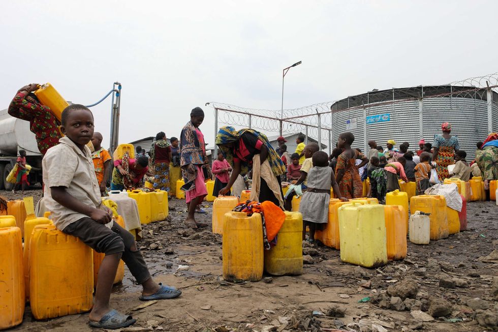 Akilimali Bruno, 8, sits on a jerry can of water at the camp for displaced people in Munigi. Water is almost nonexistent in the camp, and people say they now have to draw twice as much to ensure their health and sanitation.