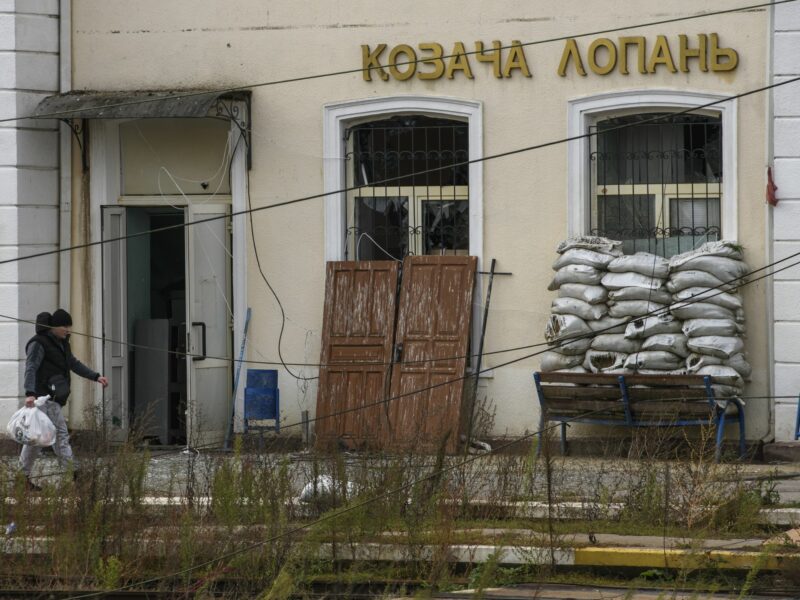 An abandoned train station has sandbags and scrap wood piled up by the windows