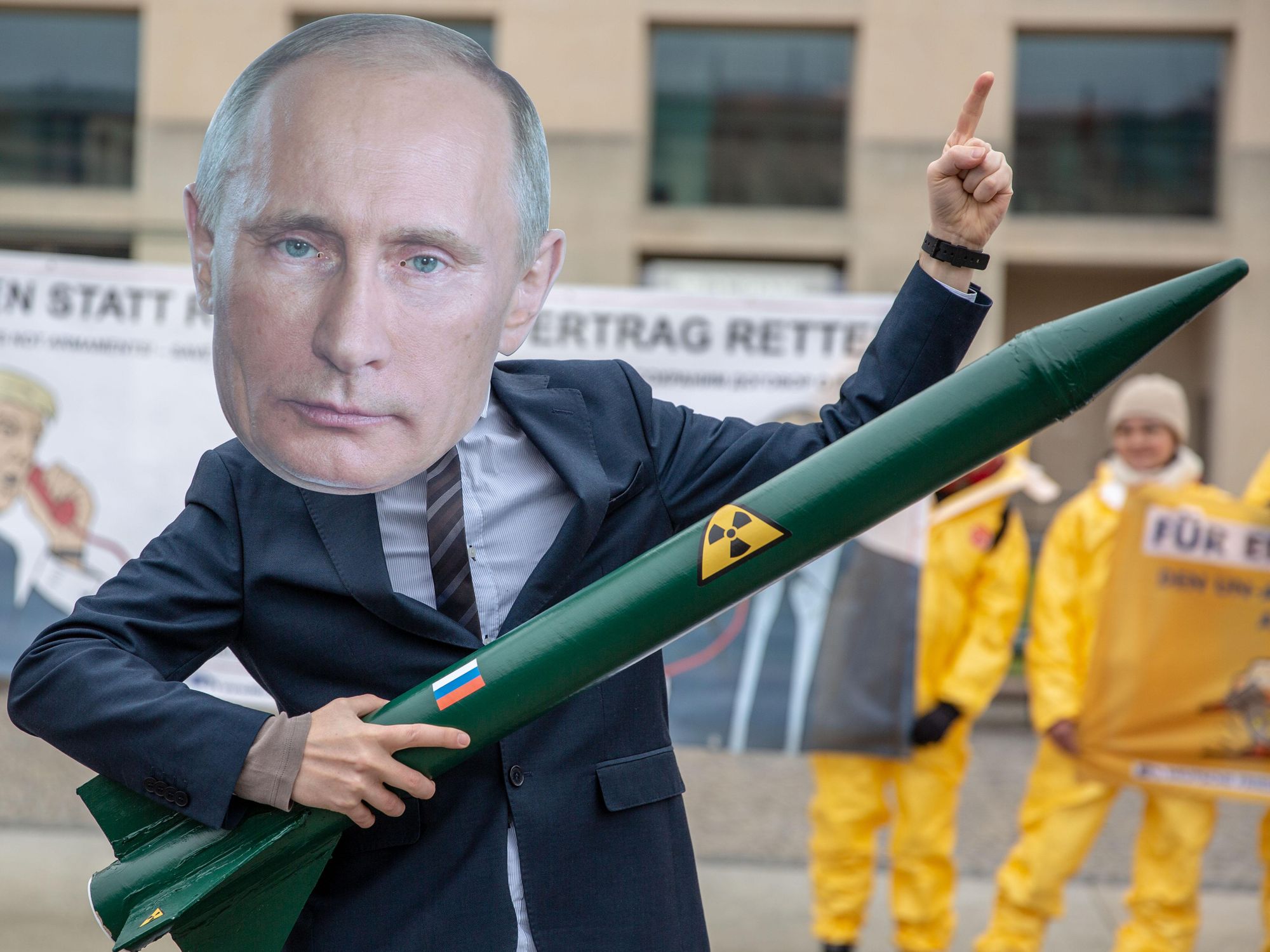 An activist wearing a Putin mask and a nuclear missile toy.