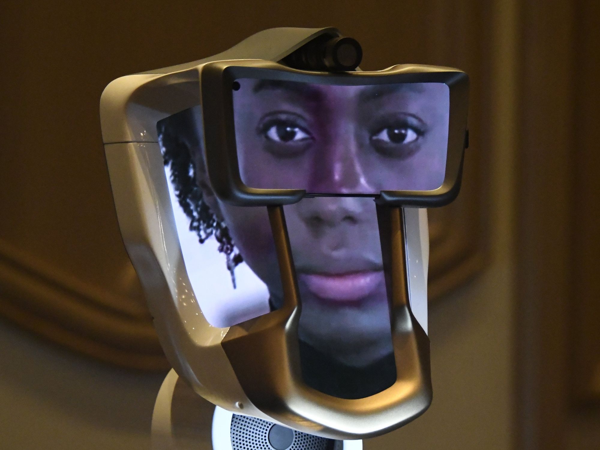 An AI face on 4 different screens with a camera at the top and a speaker at the bottom of the machine.