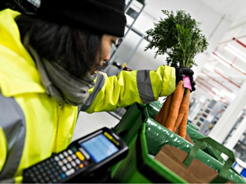 An Amazon Fresh employee packs a bunch of carrots for grocery delivery in Berlin