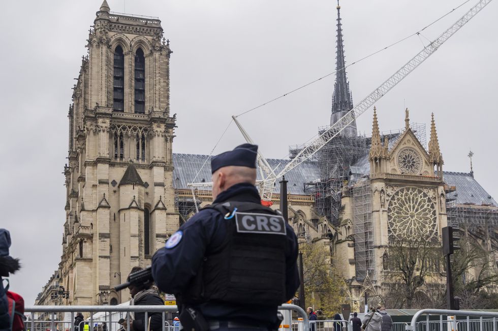 An armed policeman controls vehicle access next to the Cathedral Dame as part of the preparations for the opening ceremony. December 5, 2024, Paris, France.​