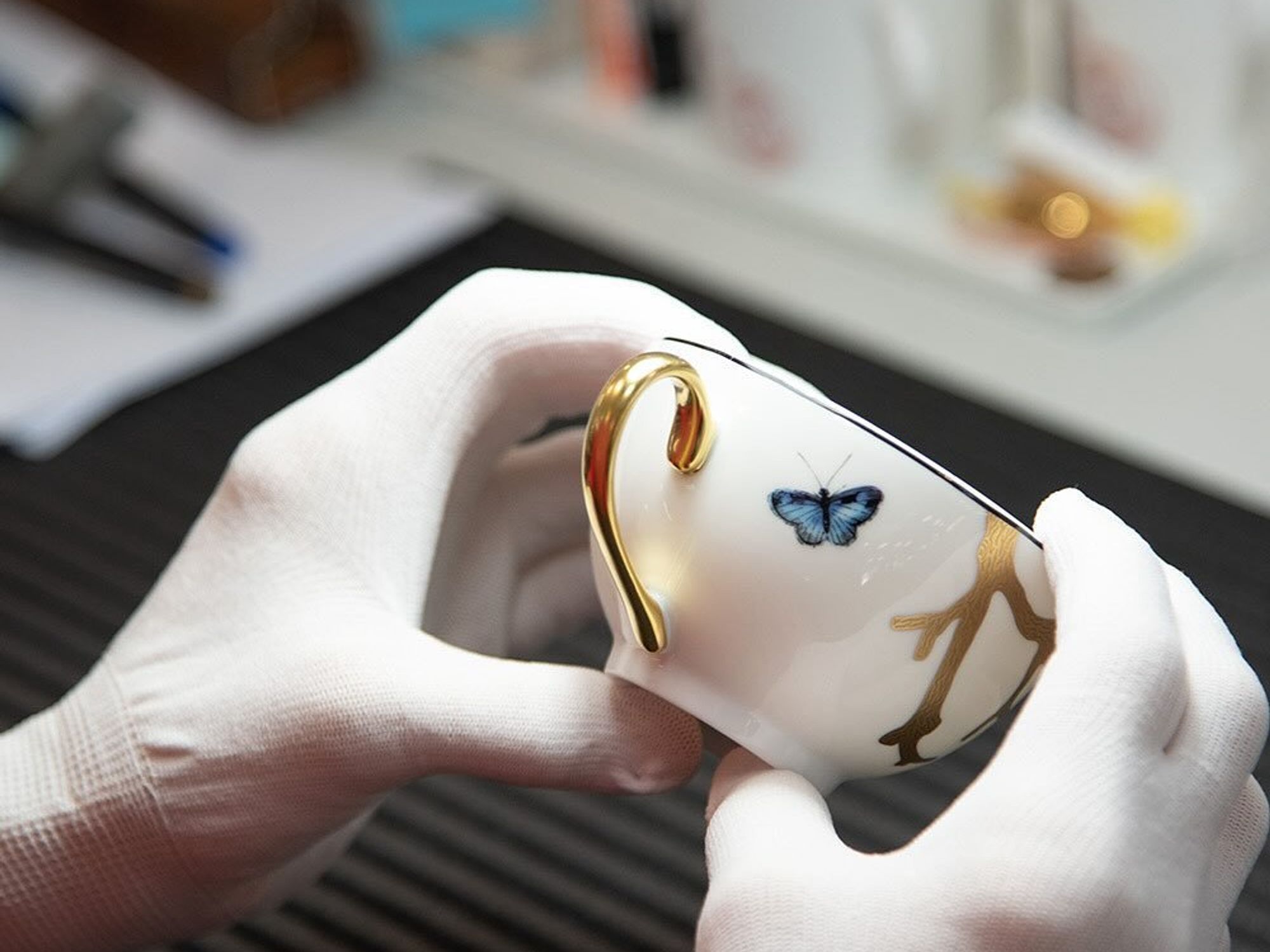 An ​artisan at the Bernardaud manufacture checking a porcelain cup.