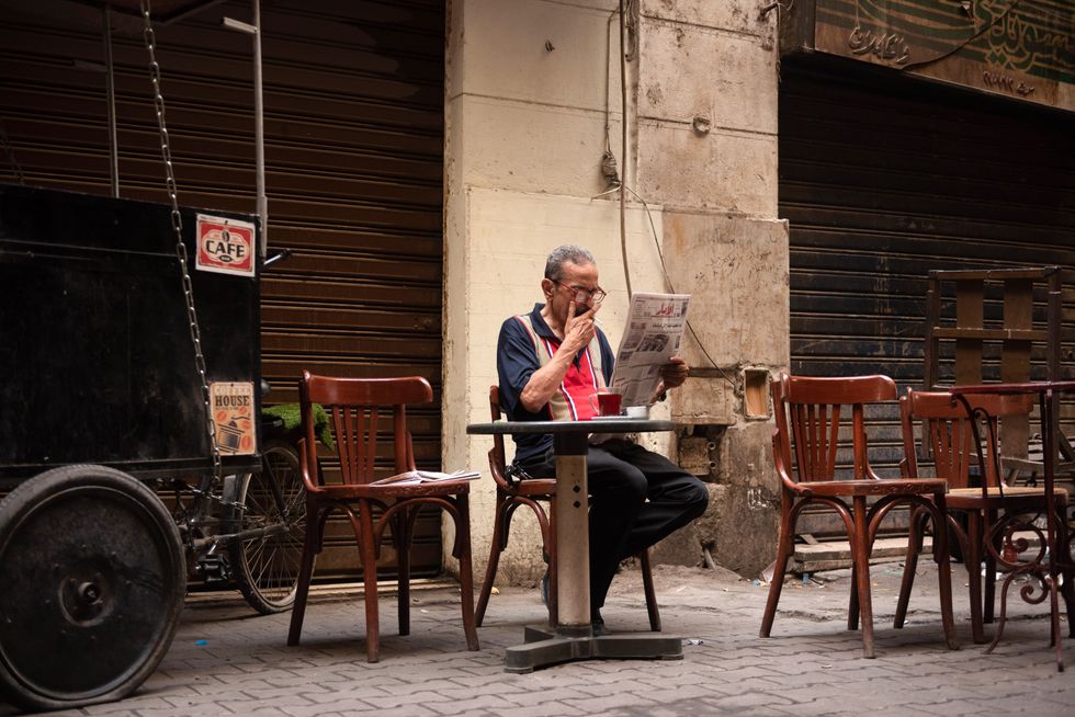 An Egyptian man smokes, drinks tea and reads a newspaper in a local cafe in Downtown Cairo.