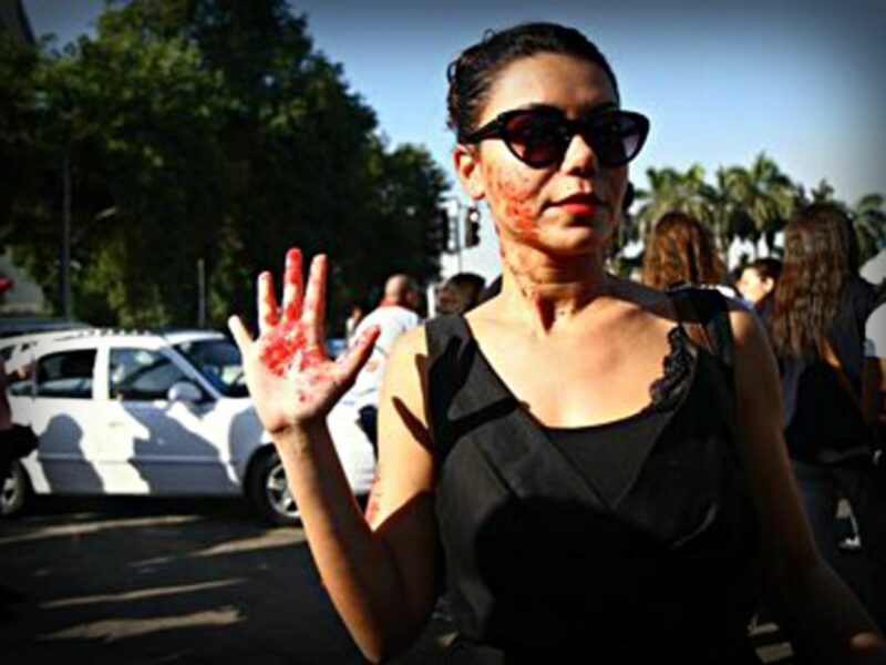 An Egyptian woman with red paint on her hand and face depicting blood during a sexual harassment protest in Cairo.