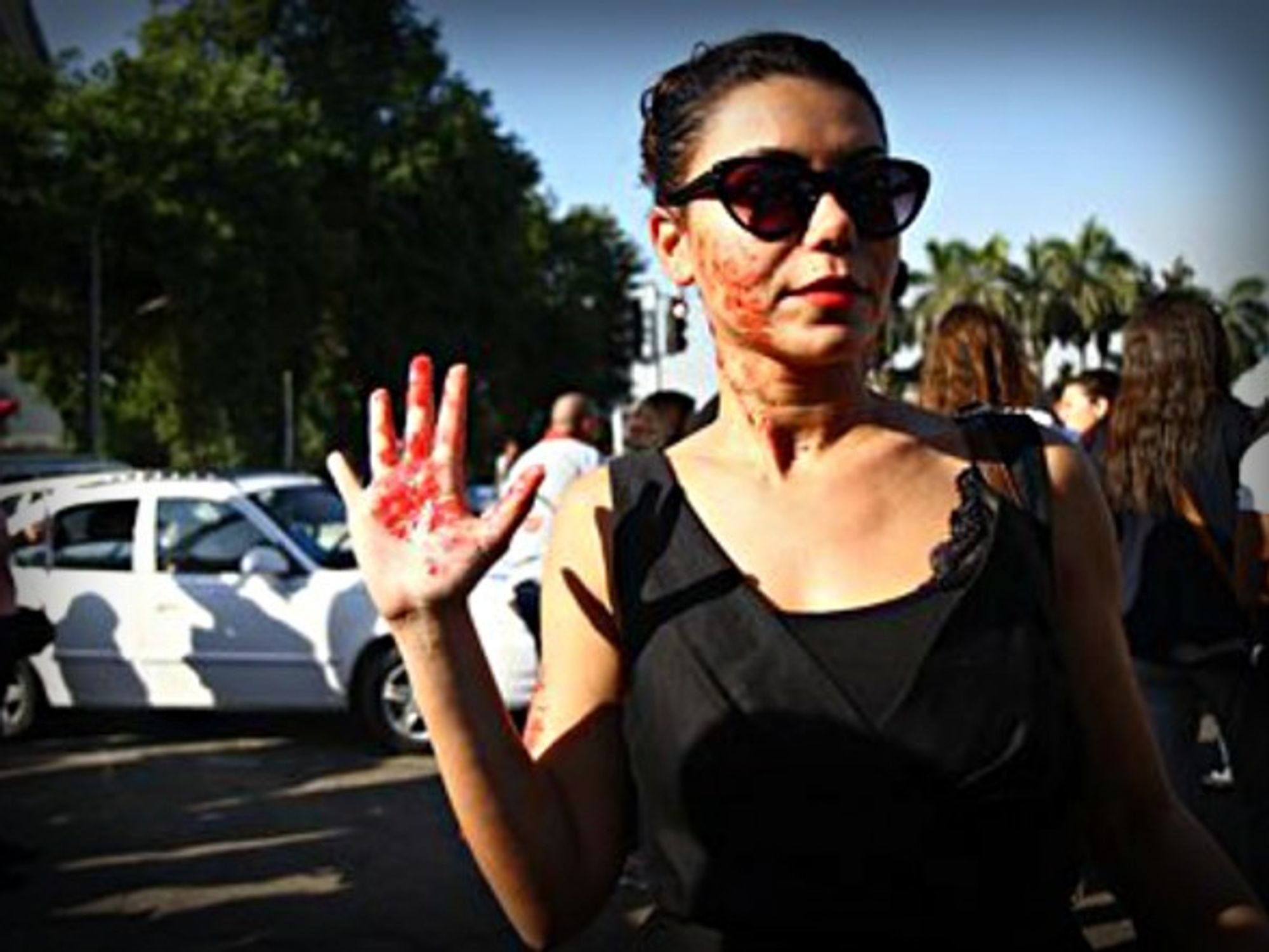 An Egyptian woman with red paint on her hand and face depicting blood during a sexual harassment protest in Cairo.