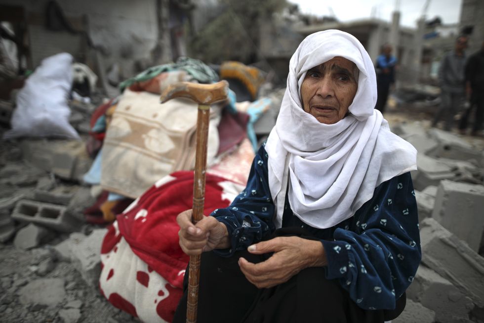 An elderly woman sits on the debris after Israeli airstrikes at Al-Maghazi refugee camp in central Gaza Strip, April 13, 2024.