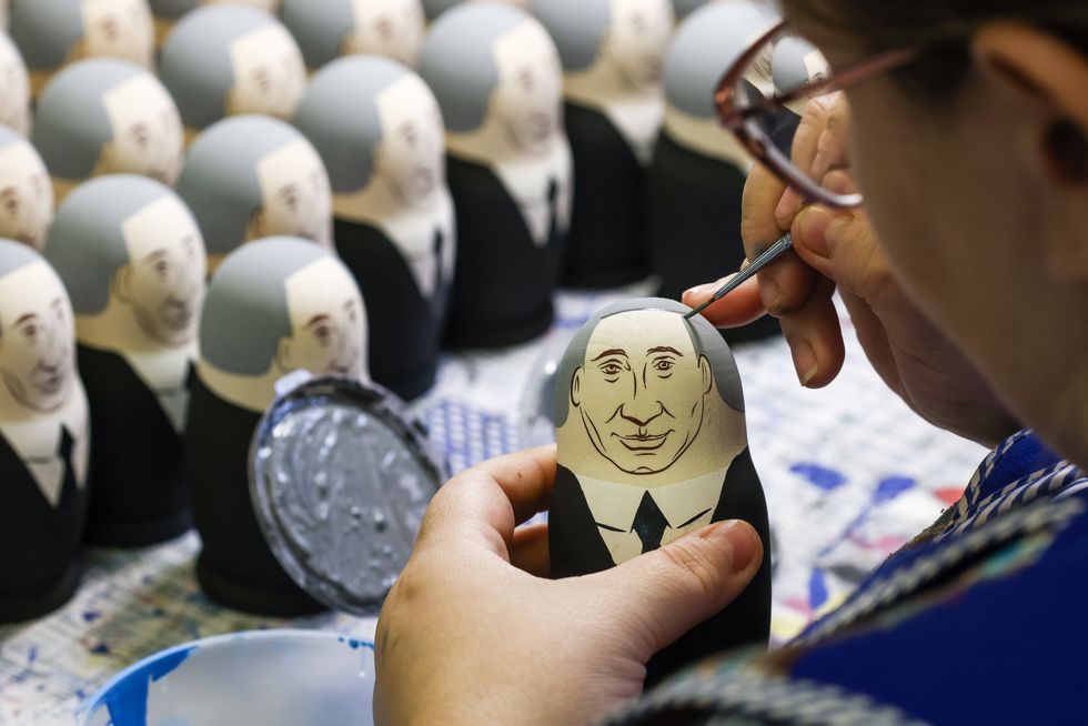 An employee paints Russian traditional matryoshka nesting dolls depicting President Puti.