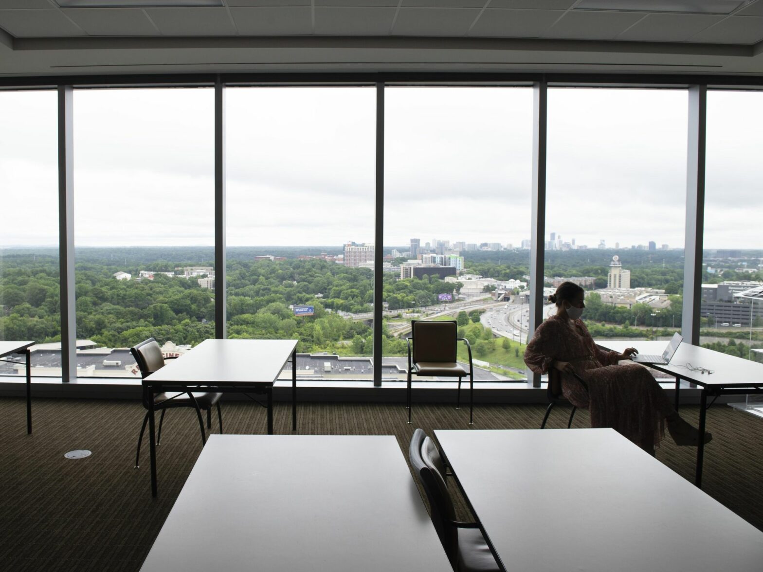 An employee works alone in a large, otherwise empty training room at an Atlanta accounting firm, where most employees now work from home with remote access to the company's computer system
