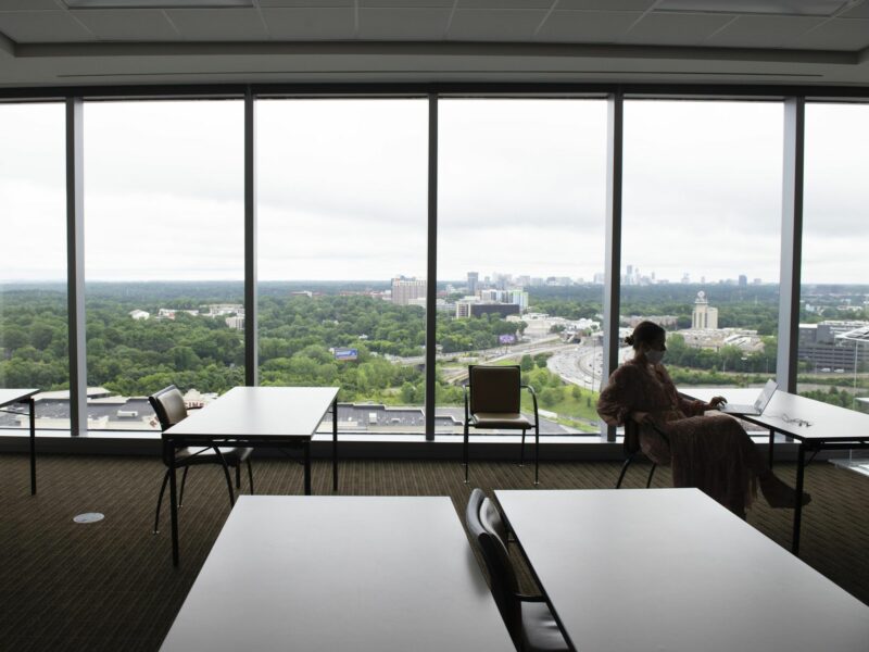 An employee works alone in a large, otherwise empty training room at an Atlanta accounting firm, where most employees now work from home with remote access to the company's computer system