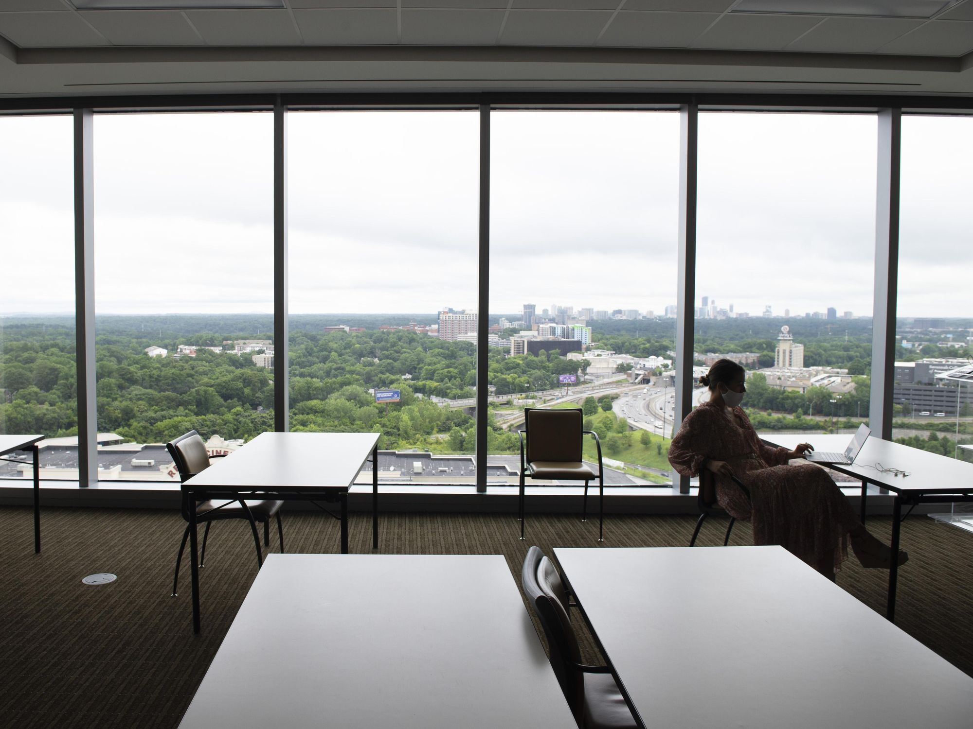 An employee works alone in a large, otherwise empty training room at an Atlanta accounting firm, where most employees now work from home with remote access to the company's computer system