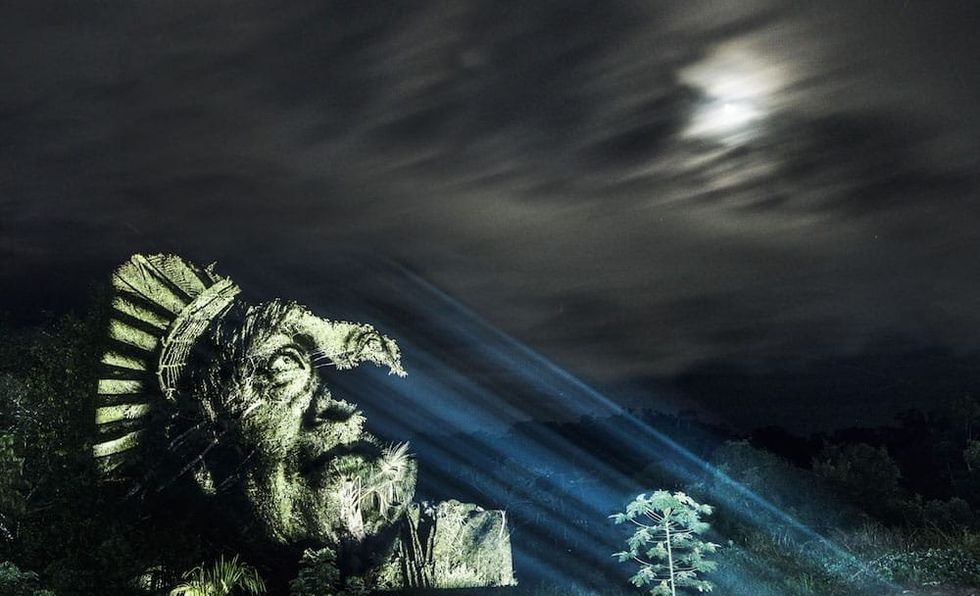 An illuminated tree sculpted in the shape of an indigenous woman.